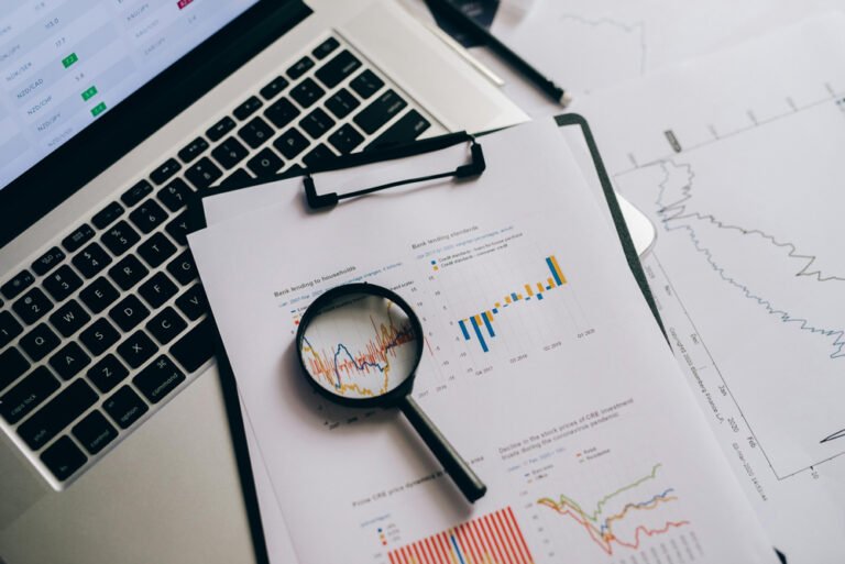 Image showing a laptop, pages with charts, and a magnifying glass, symbolising the detailed data analysis that goes into building an effective Pinterest marketing strategy.